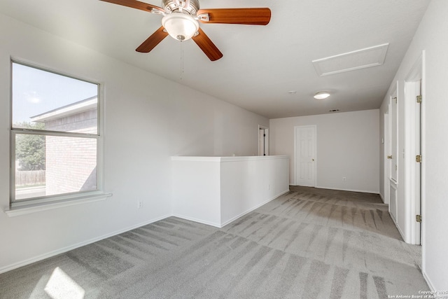 carpeted spare room with attic access and baseboards