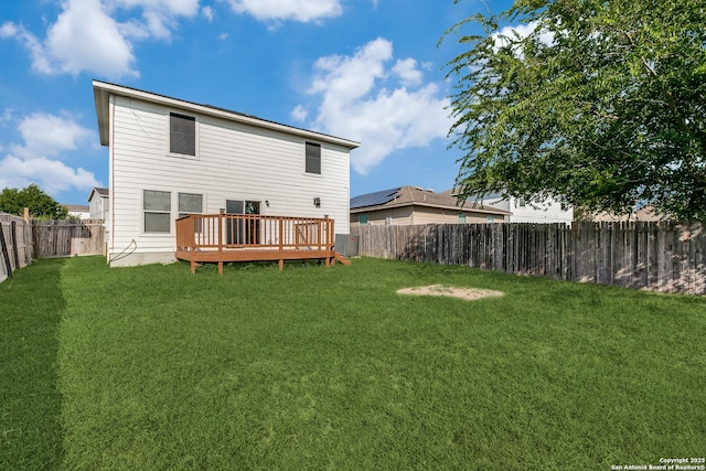 rear view of house with a fenced backyard, a wooden deck, central AC, and a yard