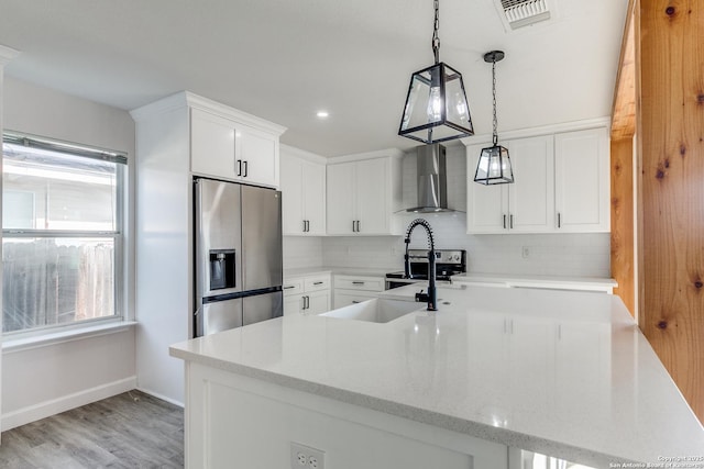 kitchen with visible vents, wall chimney exhaust hood, appliances with stainless steel finishes, white cabinetry, and a sink