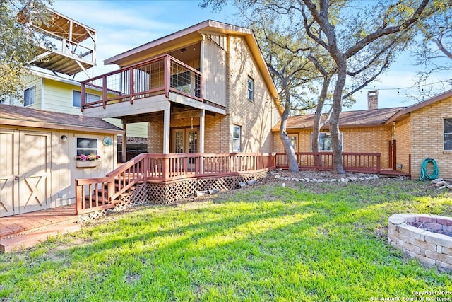 back of house with a deck, a yard, brick siding, and an outdoor structure