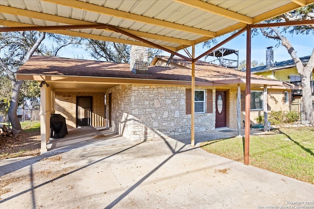 view of front facade featuring brick siding, a shingled roof, a front yard, stone siding, and driveway