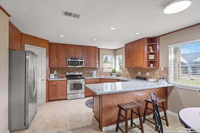 kitchen with open shelves, stainless steel appliances, visible vents, brown cabinetry, and a peninsula