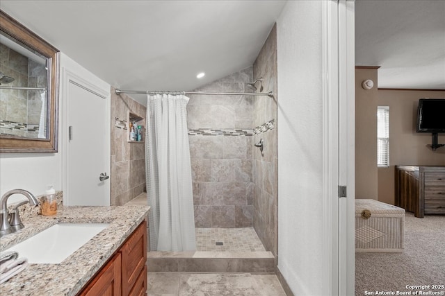 bathroom with vaulted ceiling, a tile shower, and vanity