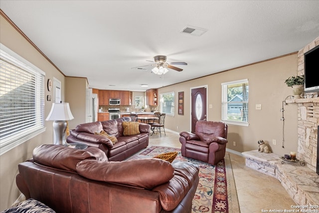 living area with crown molding, a fireplace, visible vents, and a healthy amount of sunlight