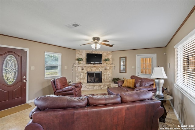 living room with ceiling fan, a fireplace, visible vents, baseboards, and ornamental molding