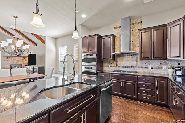 kitchen featuring stainless steel appliances, backsplash, a sink, and wall chimney range hood