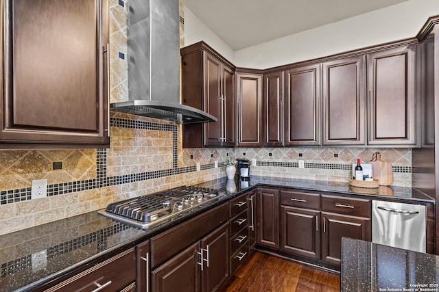 kitchen with tasteful backsplash, dark wood-style floors, dark stone countertops, wall chimney range hood, and stainless steel gas stovetop