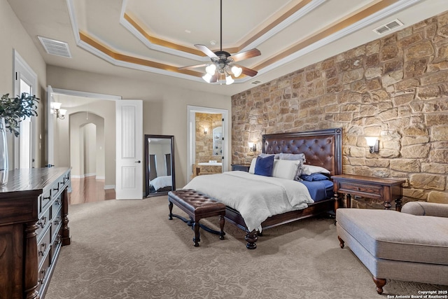 carpeted bedroom featuring arched walkways, ornamental molding, a raised ceiling, and visible vents