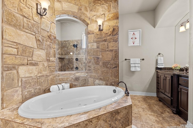 full bath with a jetted tub, vanity, and baseboards