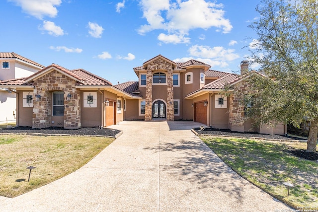 mediterranean / spanish-style home featuring driveway, stone siding, a tiled roof, an attached garage, and a front lawn