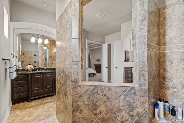 bathroom with visible vents, a tile shower, vanity, and ensuite bath