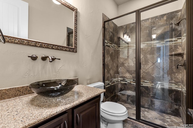 full bathroom featuring vanity, a shower stall, and toilet