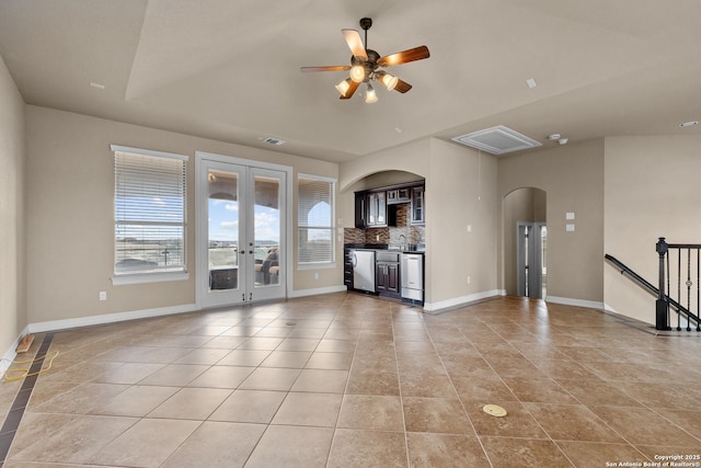 unfurnished living room featuring light tile patterned floors, baseboards, arched walkways, a ceiling fan, and french doors