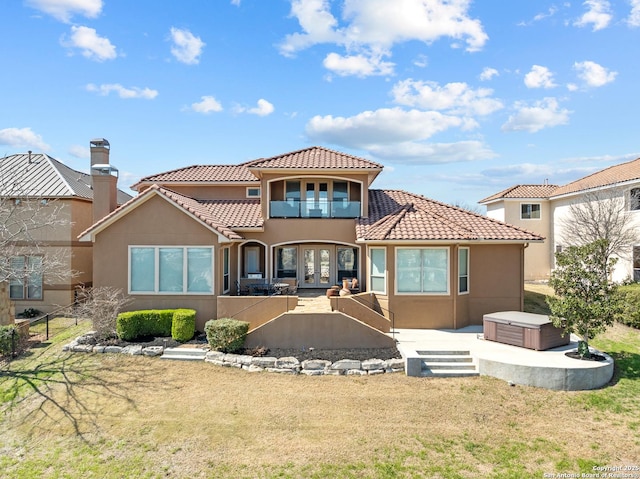 rear view of house featuring french doors, stucco siding, a hot tub, fence, and a balcony