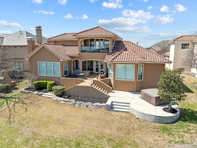 back of house with a balcony, a patio area, a hot tub, and stucco siding