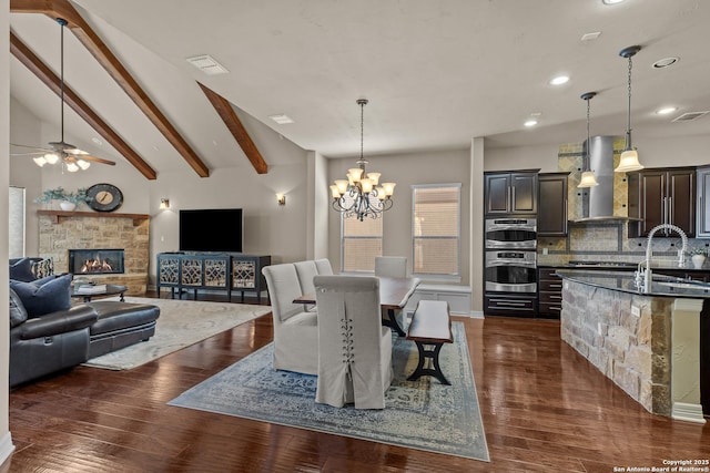 dining room featuring vaulted ceiling with beams, a fireplace, visible vents, and dark wood finished floors