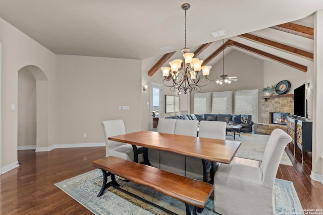 dining area featuring visible vents, dark wood finished floors, arched walkways, and a stone fireplace