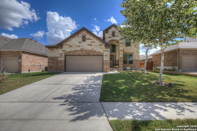 french country inspired facade with brick siding, concrete driveway, a front yard, fence, and a garage