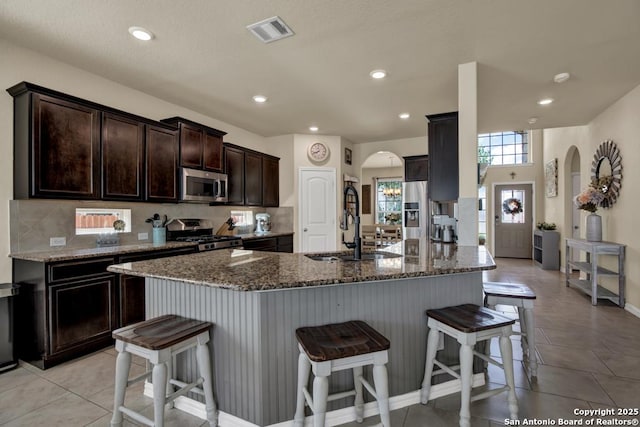 kitchen with a breakfast bar, visible vents, arched walkways, and stainless steel appliances