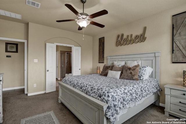 bedroom featuring a ceiling fan, dark colored carpet, visible vents, and baseboards