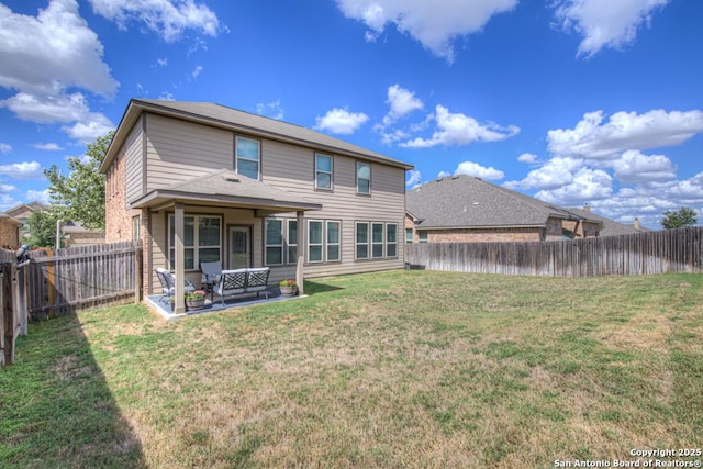 rear view of house with a fenced backyard, a patio, and a yard