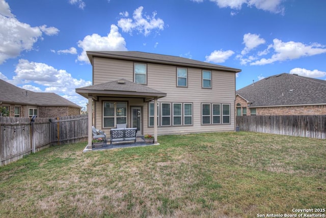 rear view of house with a fenced backyard, a yard, and a patio