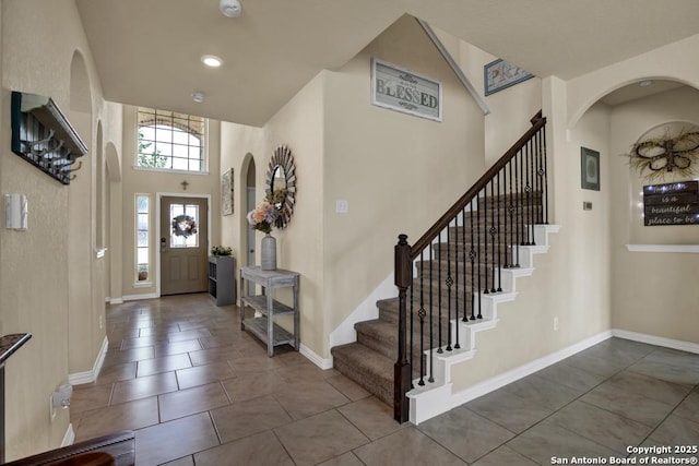 foyer entrance with tile patterned flooring, a towering ceiling, and baseboards