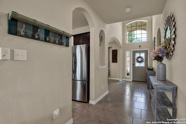 tiled foyer featuring baseboards and arched walkways