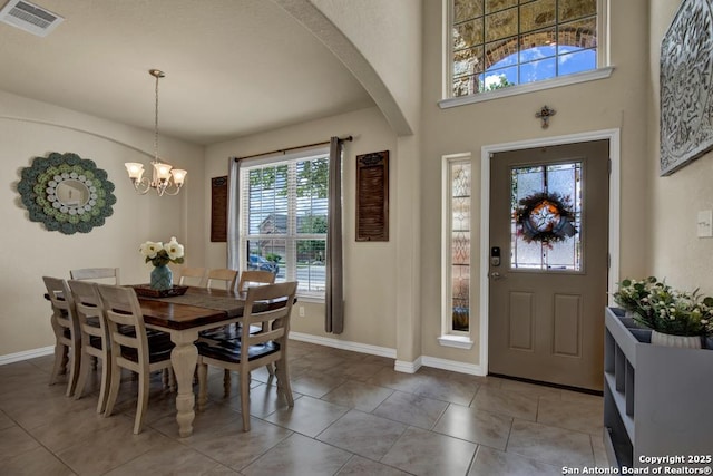 foyer entrance with arched walkways, light tile patterned floors, visible vents, an inviting chandelier, and baseboards