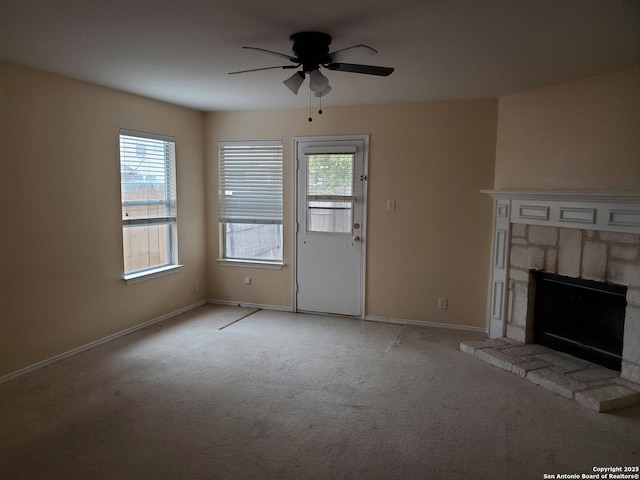 unfurnished living room featuring baseboards, ceiling fan, a fireplace, and light colored carpet