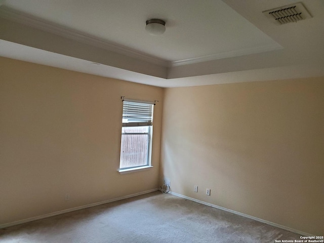 carpeted empty room with baseboards, visible vents, a raised ceiling, and crown molding