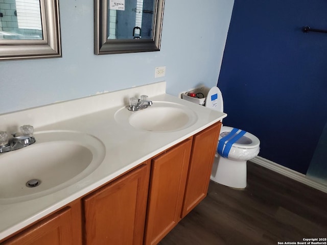 full bathroom with double vanity, wood finished floors, a sink, and toilet