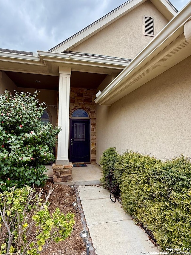 view of exterior entry with stone siding and stucco siding