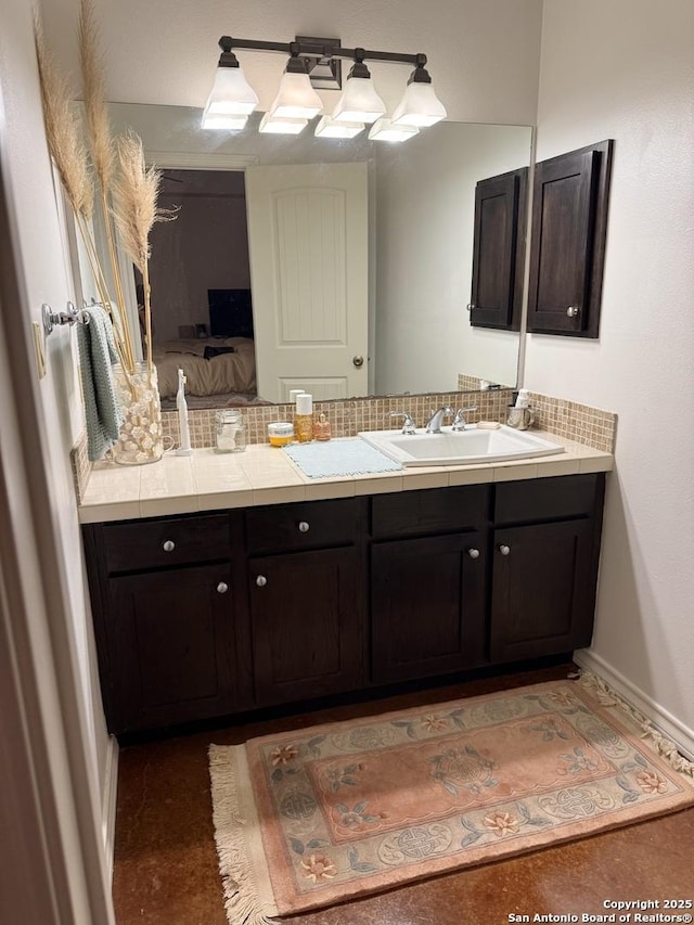 bathroom featuring baseboards, decorative backsplash, connected bathroom, and vanity