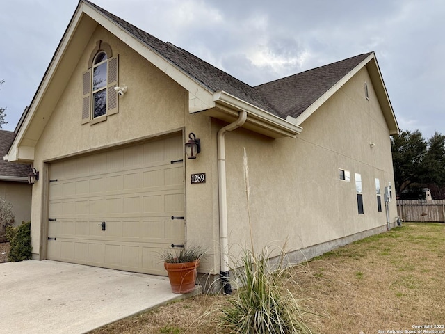 view of home's exterior featuring concrete driveway, roof with shingles, and stucco siding