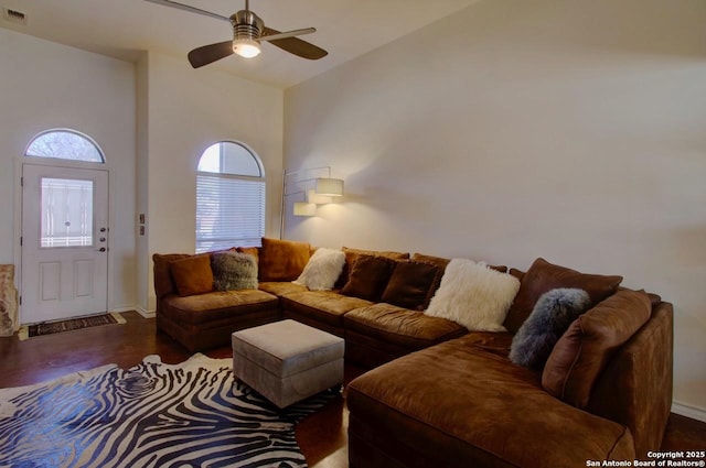 living area featuring visible vents, baseboards, a ceiling fan, wood finished floors, and high vaulted ceiling