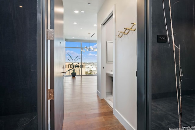 hall with a wall of windows, recessed lighting, wood finished floors, and baseboards