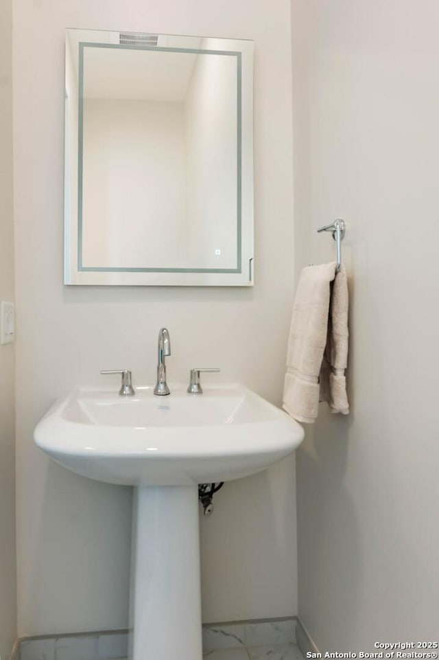 bathroom featuring marble finish floor, a sink, and baseboards