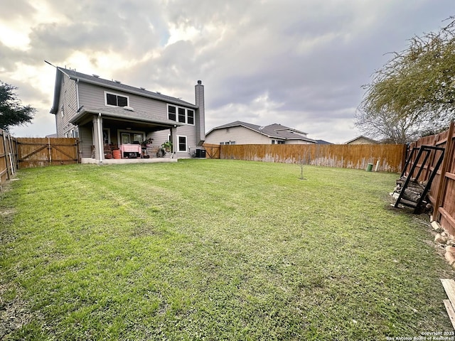 view of yard with a patio area, a fenced backyard, and a gate