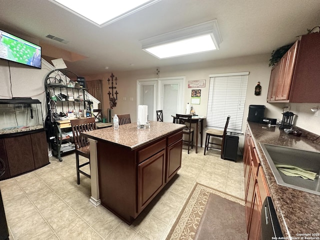 kitchen with dark countertops, a breakfast bar area, visible vents, and a sink