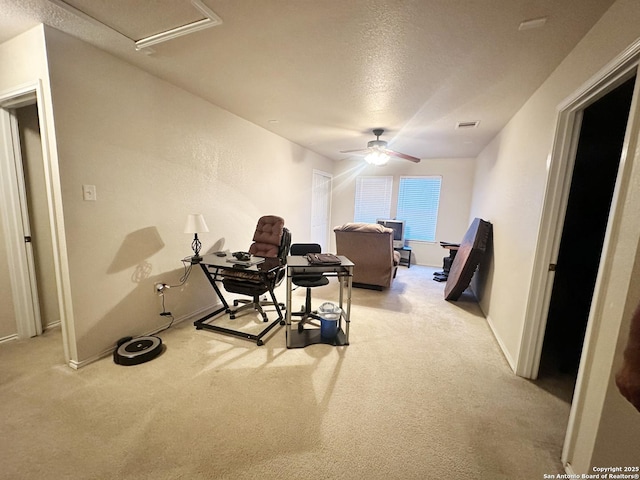 office space with a textured ceiling, light colored carpet, a ceiling fan, baseboards, and visible vents