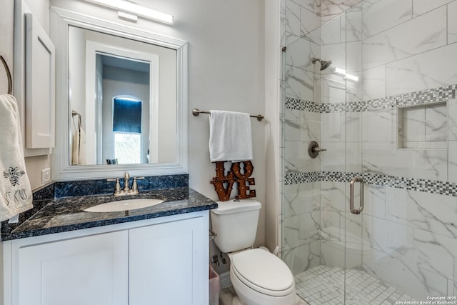 full bath with toilet, a marble finish shower, and vanity