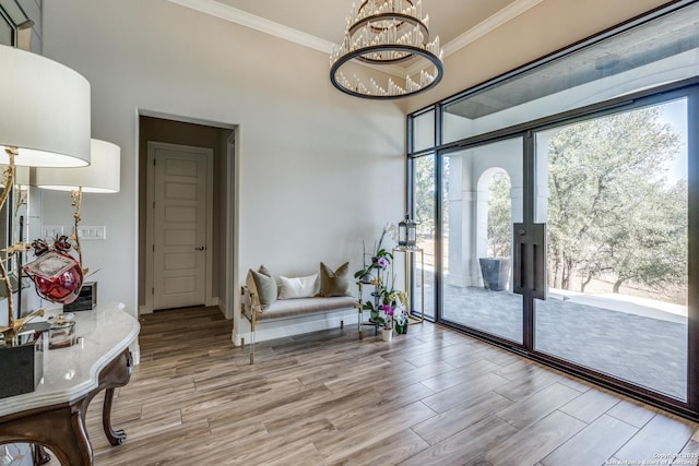 interior space with ornamental molding, baseboards, an inviting chandelier, and wood finished floors