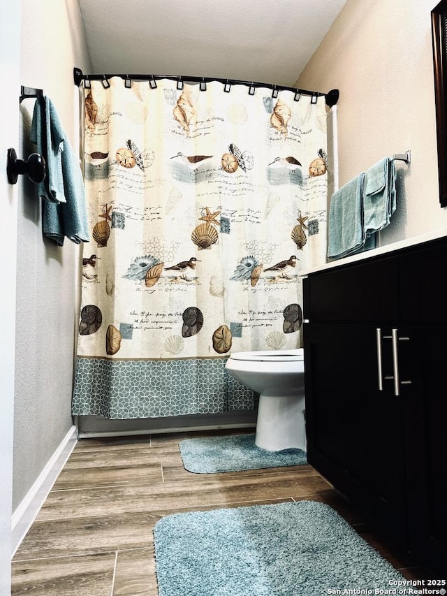 bathroom with toilet, a shower with shower curtain, and wood finished floors