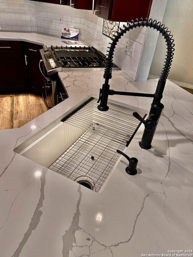 interior details featuring light stone counters, backsplash, and gas stove