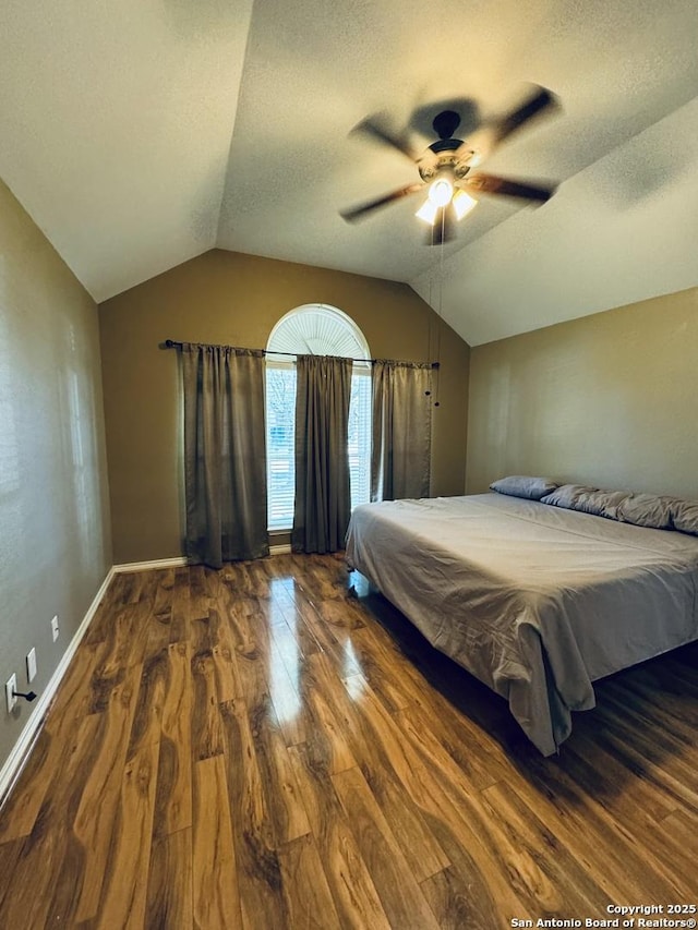 unfurnished bedroom with wood finished floors, baseboards, lofted ceiling, ceiling fan, and a textured ceiling