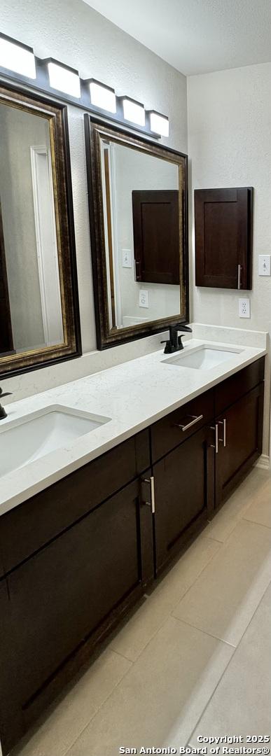 bathroom with tile patterned flooring, double vanity, and a sink