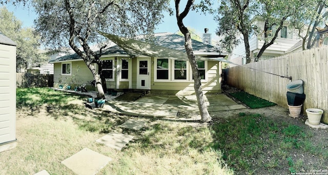 back of house with a patio, a fenced backyard, and a chimney