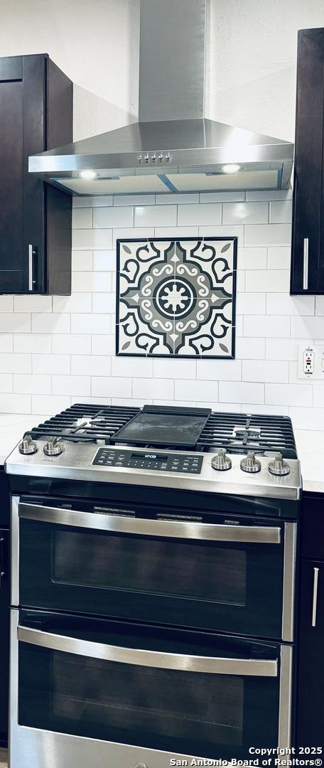 kitchen featuring decorative backsplash, double oven range, light countertops, and wall chimney exhaust hood