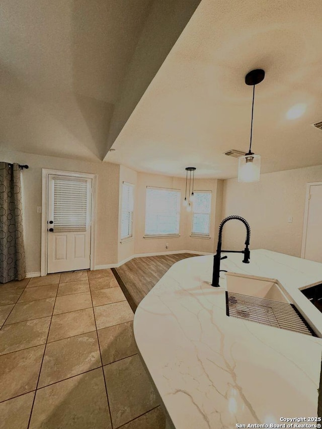 interior space featuring hanging light fixtures, visible vents, baseboards, and light stone counters